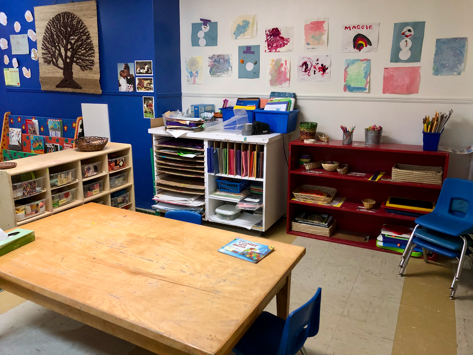 Classroom with a table and several shelves of books and craft materials