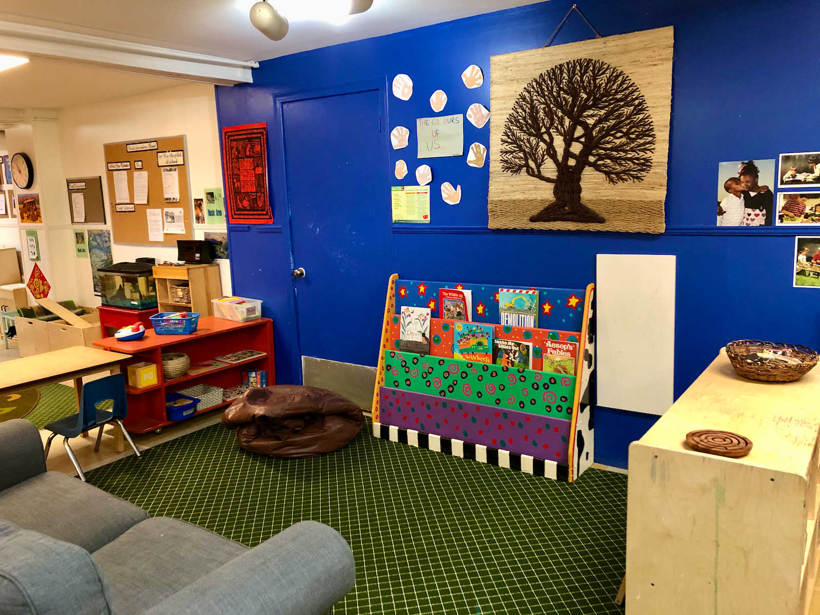 Inside of the school with a sofa, books, a blue wall with arts and crafts all around