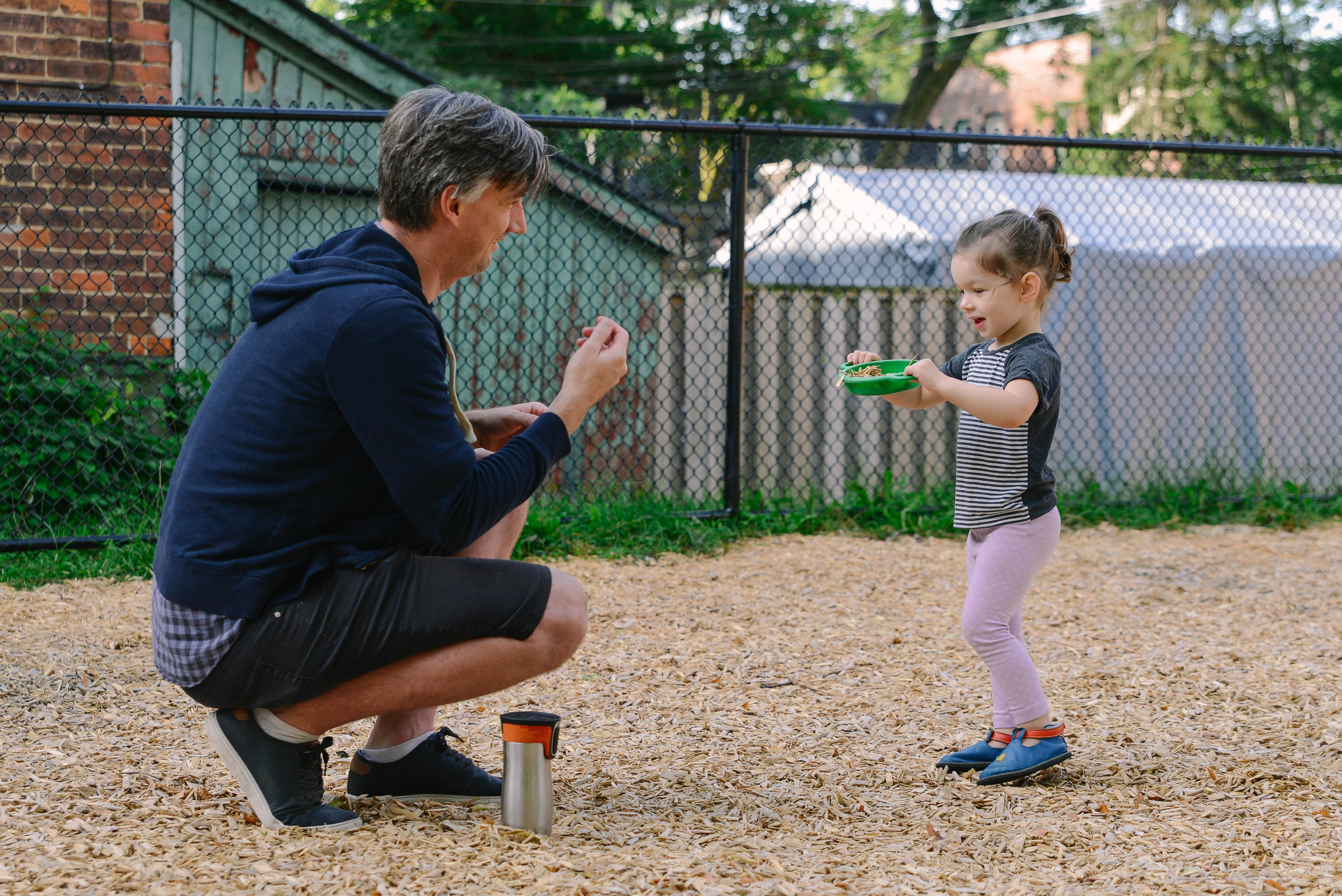 Adult and a kid in a playground playing with woodchips